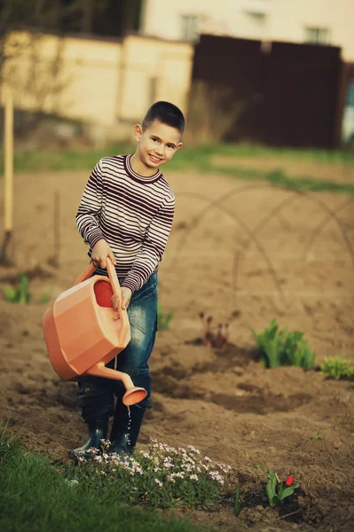 Little helper drenken bloemen in de tuin — Stockfoto