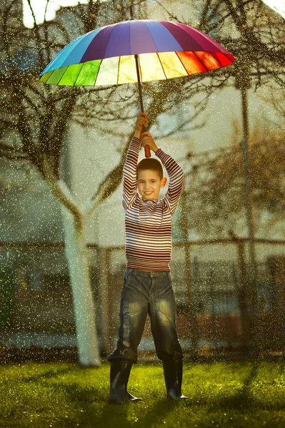 Little girl with a rainbow umbrella in park — Stock Photo, Image