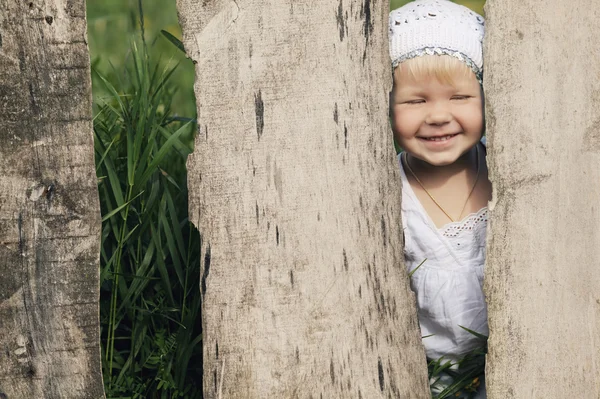 Klein meisje en houten hek — Stockfoto