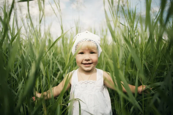 Schattig klein meisje in hoog gras — Stockfoto