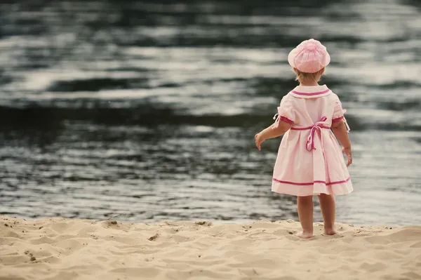 Маленькая девочка, стоящая спиной на пляже — стоковое фото