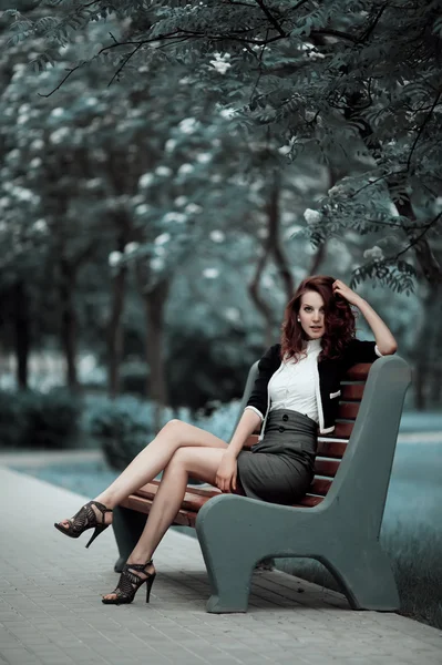 Jovem menina bonita sentado no banco — Fotografia de Stock