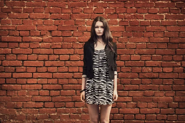 Hermosa chica cerca de la pared de ladrillo rojo — Foto de Stock