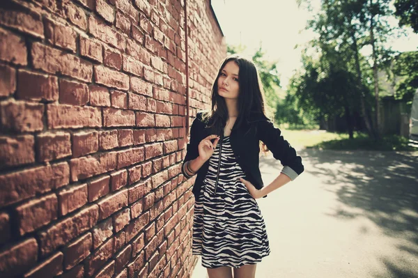 Beautiful girl near red brick wall — Stock Photo, Image