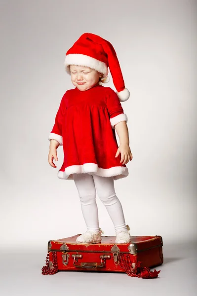 Crying girl standing on red suitcase with gifts — Stock Photo, Image