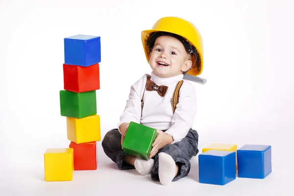 Little engineer with helmet plays with cubes — Stock Photo, Image