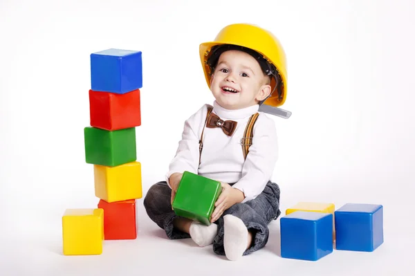 Pequeño ingeniero con casco juega con cubos — Foto de Stock