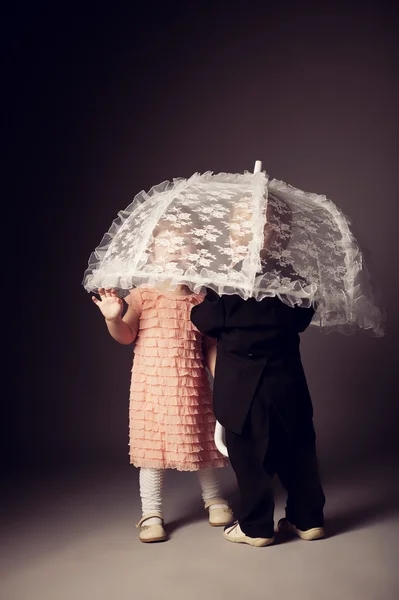 Маленький веселый мальчик и девочка под зонтиком — стоковое фото