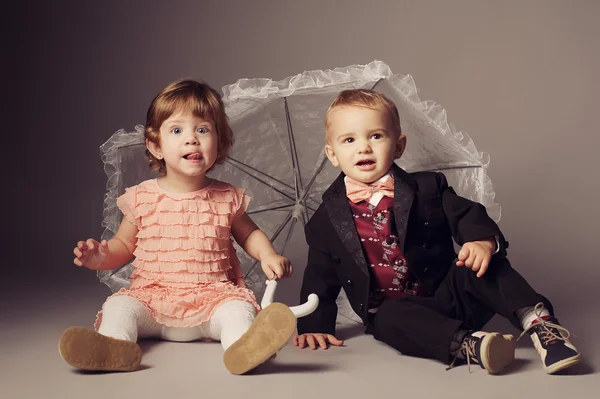 Malý vtipný chlapec a dívka pod deštníkem — Stock fotografie