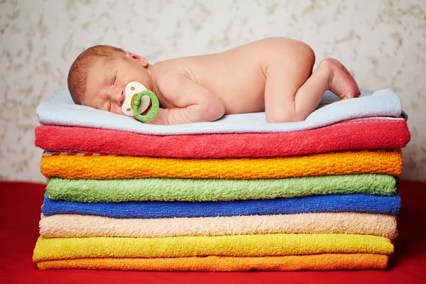 Bebê recém-nascido bonito deitado em toalhas coloridas — Fotografia de Stock