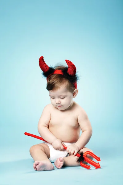 Дитина з диявольськими рогами на синьому фоні — стокове фото