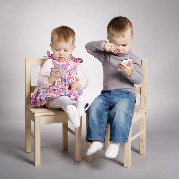 Menino e menina brincando com telefones celulares — Fotografia de Stock