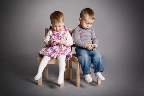 Menino e menina brincando com telefones celulares — Fotografia de Stock