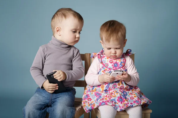 Menino e menina brincando com telefones celulares — Fotografia de Stock