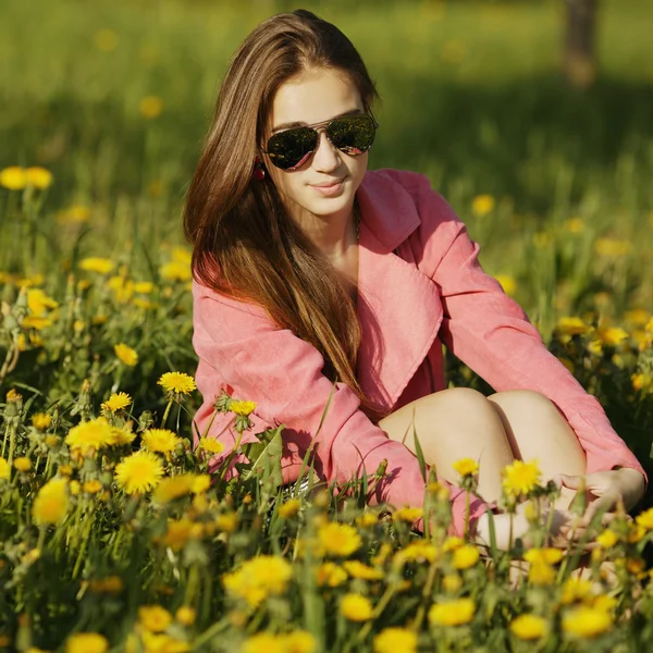 Hermosa chica con gafas de sol en el campo de diente de león —  Fotos de Stock