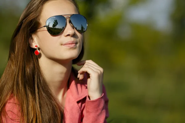 Vacker flicka med solglasögon i maskros fält — Stockfoto