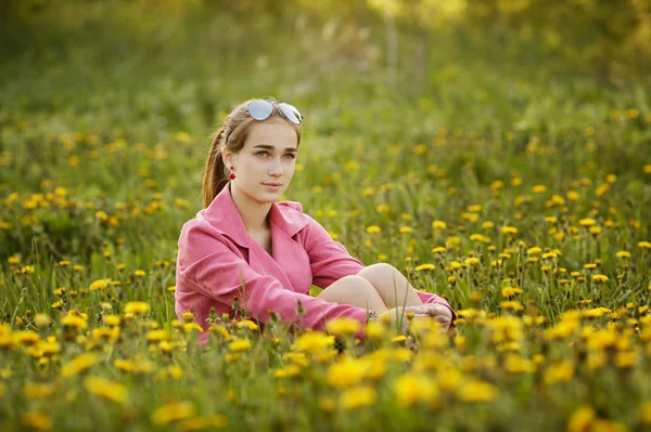 Hermosa chica con gafas de sol en el campo de diente de león —  Fotos de Stock