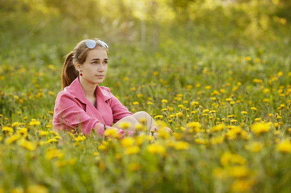 Красивая девушка в солнцезащитных очках в поле одуванчиков — стоковое фото
