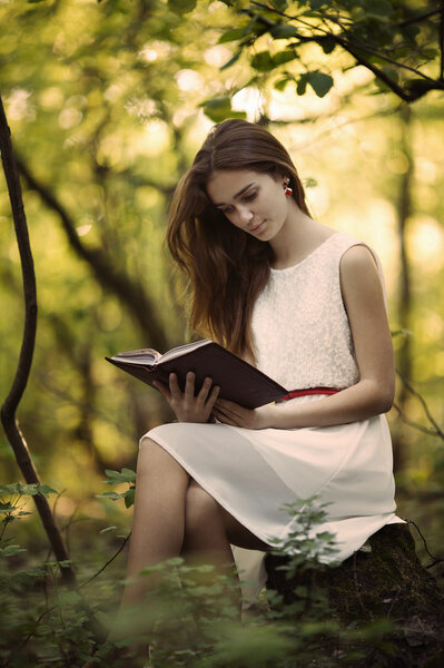 beautiful girl with book in the forest