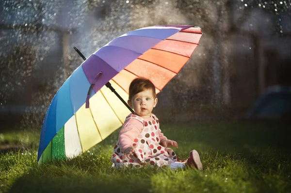 Menina com um guarda-chuva arco-íris no parque — Fotografia de Stock