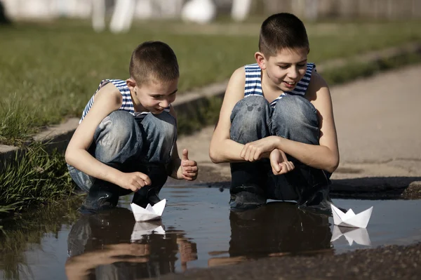 Meninos brincando com barcos de papel na poça — Fotografia de Stock