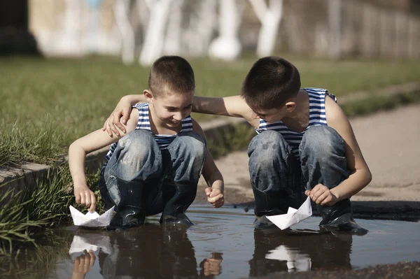 Little boys playing with paper boats in puddle — Stock Photo, Image
