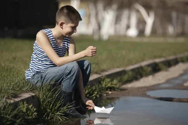 Niño juega con barcos de papel en charco —  Fotos de Stock