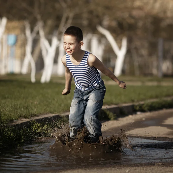 Kleine jongen springen in Plas — Stockfoto