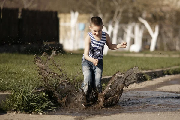 Little boy jumping in puddle — Stock Photo, Image