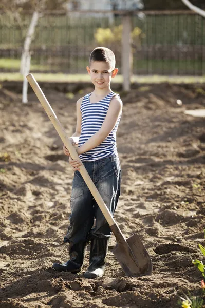 Счастливый мальчик, работающий с сапогом в саду — стоковое фото