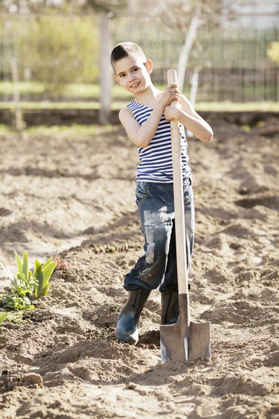 Heureux garçon travaillant avec la pelle dans le jardin — Photo