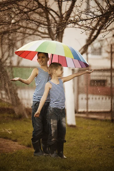 Two boys with rainbow umbrella in park — Stock Photo, Image