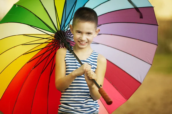 快乐的男孩，在公园里的彩虹伞 — 图库照片