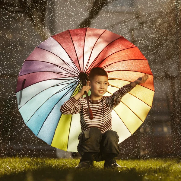 Šťastný chlapec s duhový deštník v parku — Stock fotografie