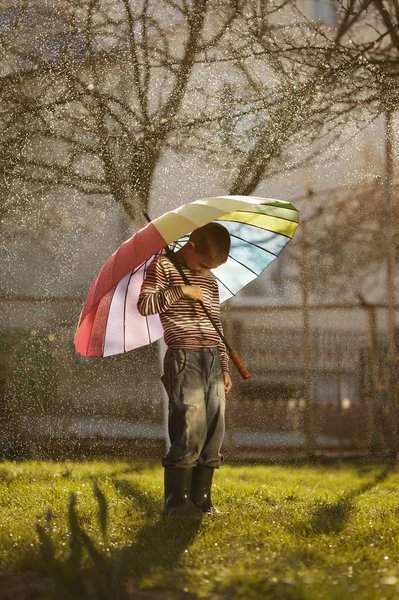 Sad boy with colorful rainbow umbrella — Stock Photo, Image