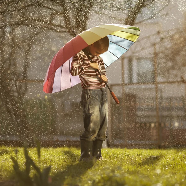 Sad boy with colorful rainbow umbrella — Stock Photo, Image