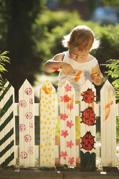 Little girl paints fence — Stock Photo, Image