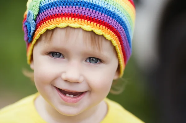 Söt liten flicka stående med rainbow hatt — Stockfoto