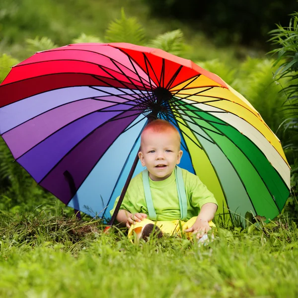 Menino bonito sob guarda-chuva colorido — Fotografia de Stock