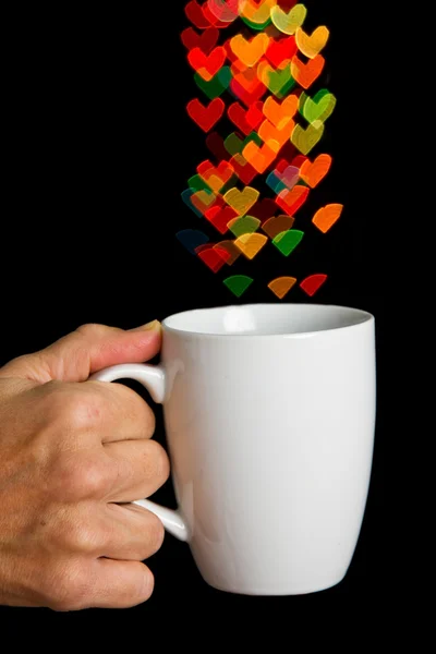 Hand holding white cup with bokeh heart shapes — Stock Photo, Image