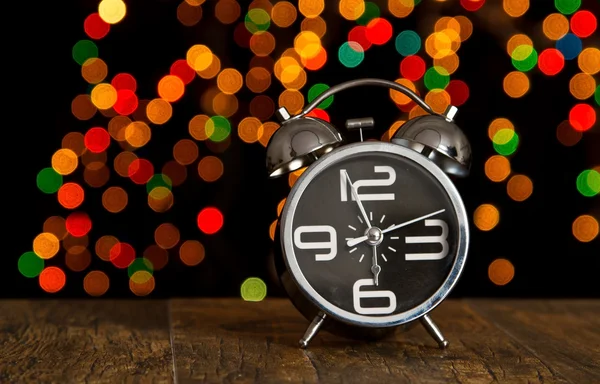 Bokeh spots of lights with alarm clock on wood — Stock Photo, Image