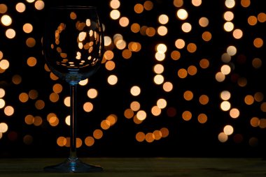 Wine glass on wooden table with dark and bokeh background clipart