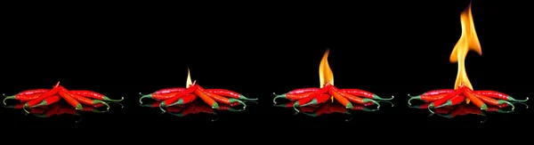 Červené chilli na černém povrchu s plameny — Stock fotografie