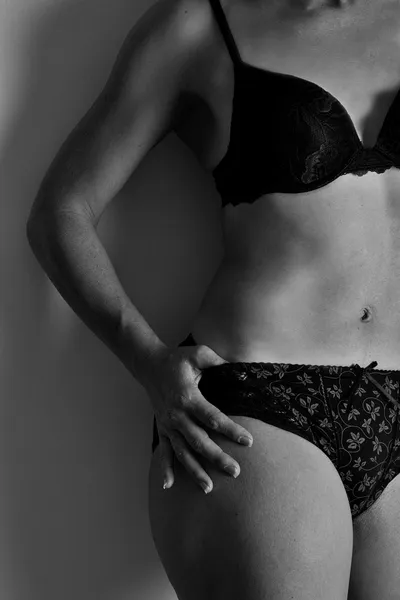 Woman in black underwear stand against wall artistic conversion — Stock Photo, Image