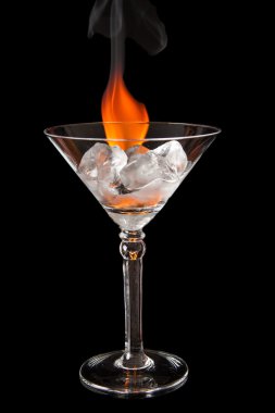 Ice cubes in glass with flame on shiny black surface clipart