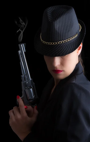 Опасная женщина в черном с серебряным дымящимся пистолетом — стоковое фото