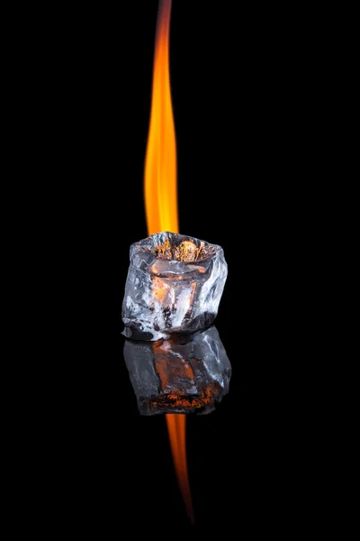 Ice cube with flame on shiny black surface
