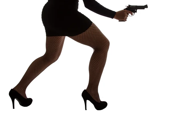 Piernas de mujer peligrosa con pistola y zapatos negros silueta — Foto de Stock