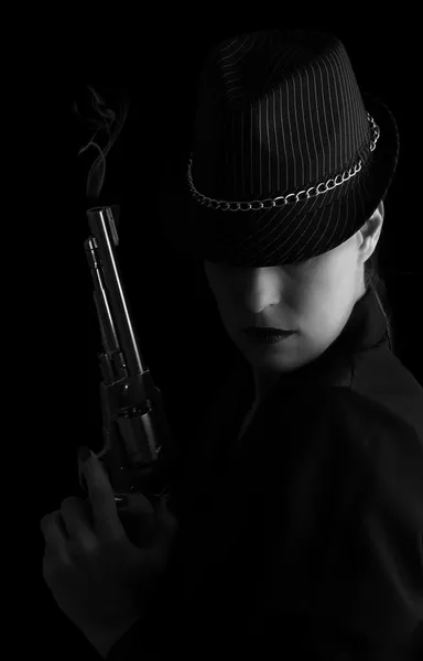 Femme dangereuse en noir avec pistolet fumeur argent — Photo