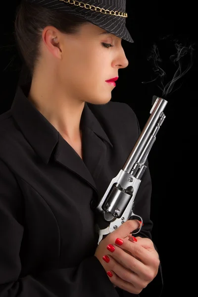 Опасная женщина в черном с серебряным дымящимся пистолетом — стоковое фото